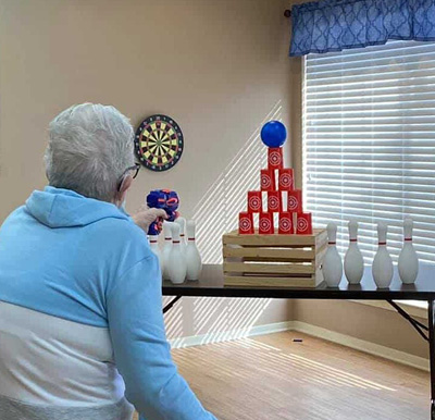 Senior woman plays a game with a Nerf gun at a senior living community in North Richland Hills, Texas.