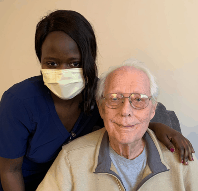 A senior living caregiver posing with a smiling resident