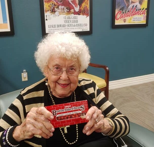 Senior woman smiles in the movie theatre room with her candy at senior living facility in Baytown, Texas.