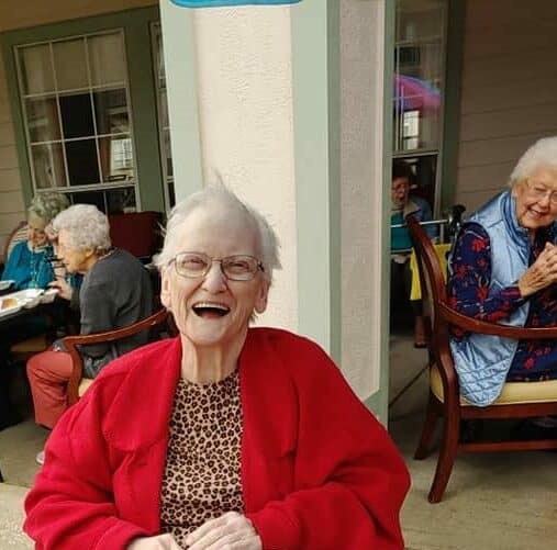 Senior woman laughing while outside with friends at a senior living facility in Baytown, Texas.