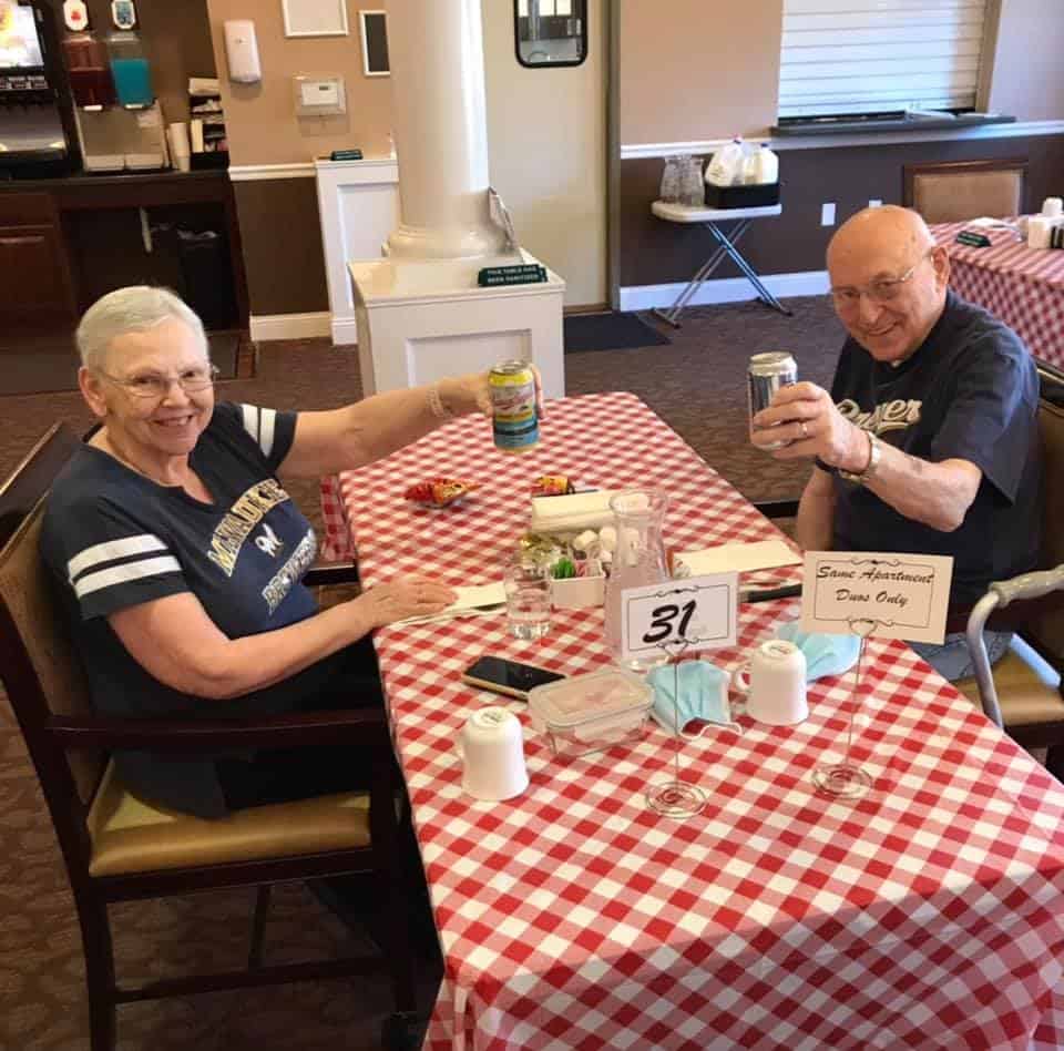 Senior man and woman cheers together while eating at a senior living community in Fitchburg, Wisconsin.