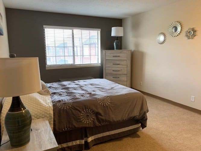 Apartment bedroom with bed, side table and lamp and dresser