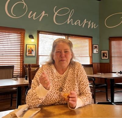 senior woman smiles while eating a treat in the dining room