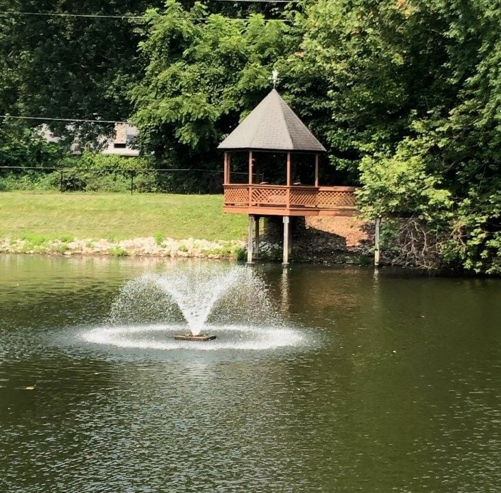 outdoor gazebo overlooking a pond with a fountain