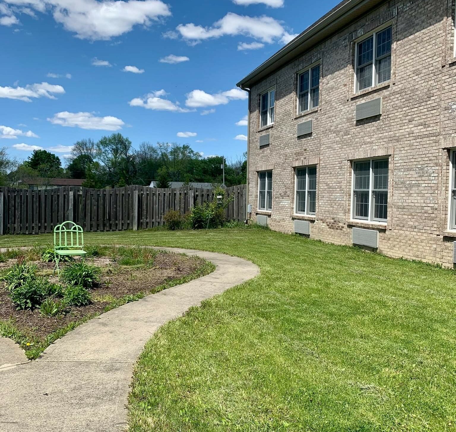 Outdoor courtyard with walking path and decorative chair at a senior living community in Indianapolis, Indiana.