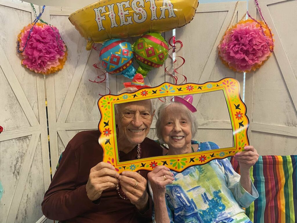 A senior woman and senior man pose together during a fiesta-themed party