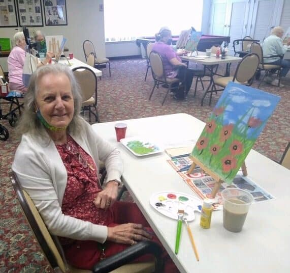 Senior woman smiles with her painting at a senior living facility in Fairfield, Ohio.