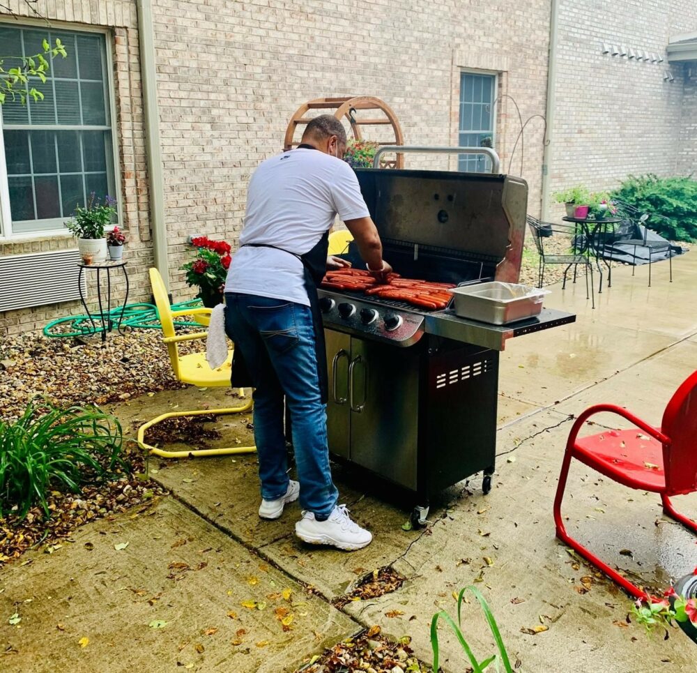 An employee cooks hot dogs outside on the grill at a senior living community in Indianapolis, Indiana.