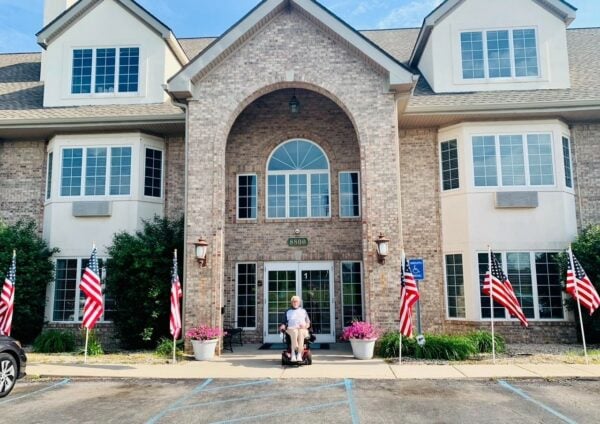 Resident poses in front of senior living community building.
