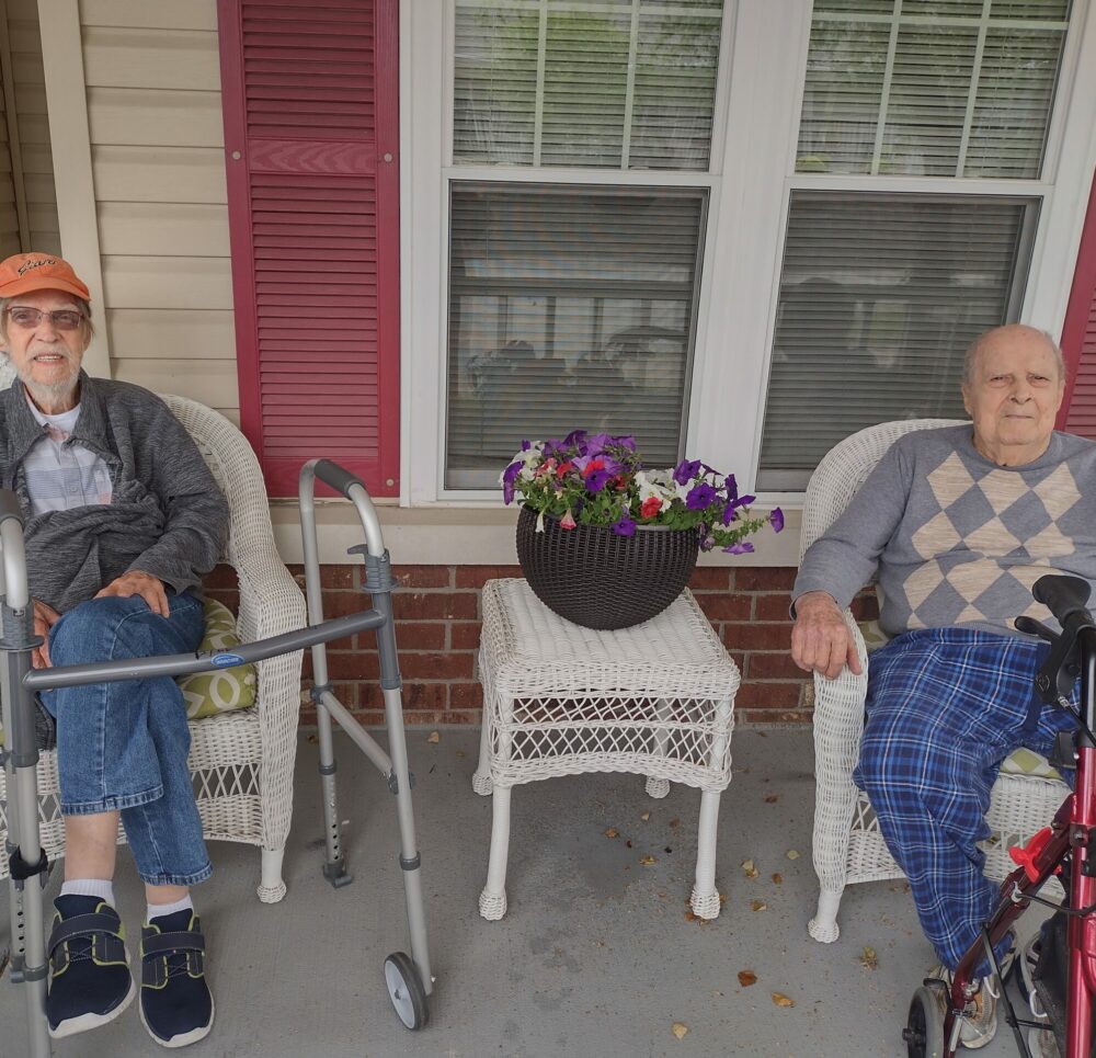 Two senior men at a front porch social at a senior living community in Jeffersonville, Indiana.