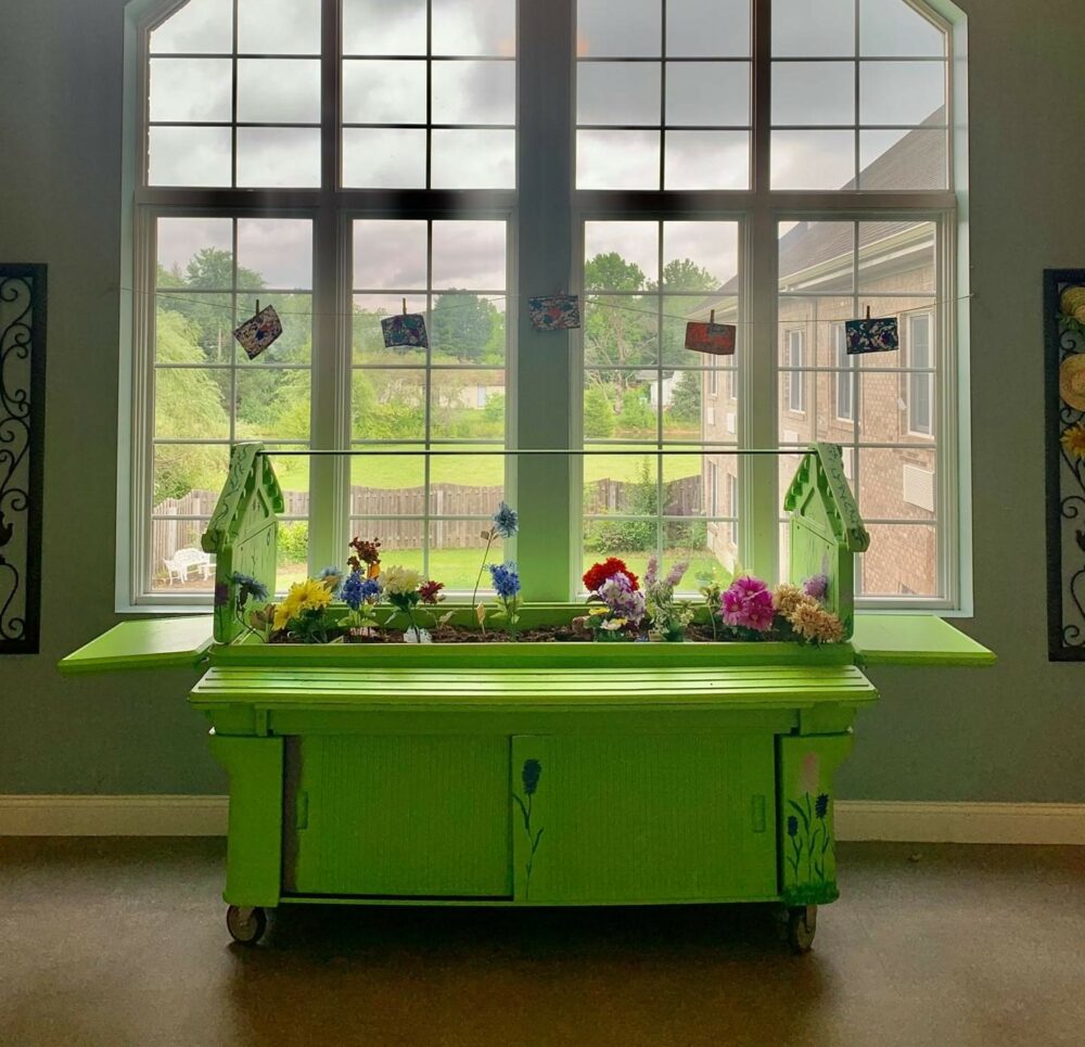 An indoor garden bed in front of a large window at a senior living community in Indianapolis, Indiana.