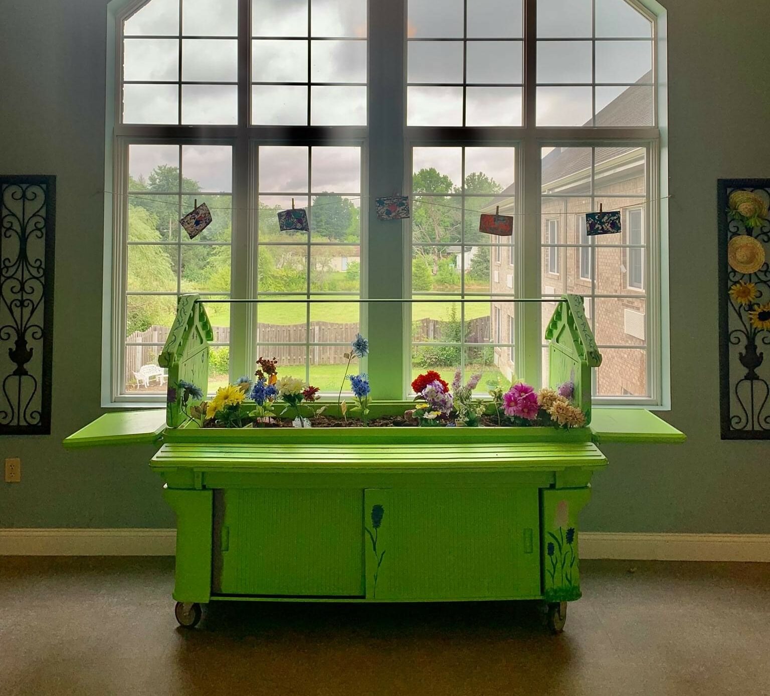 An indoor garden bed in front of a large window at a senior living community in Indianapolis, Indiana.