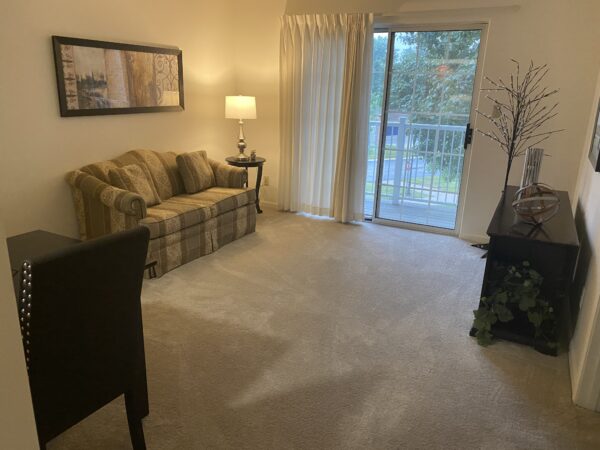 Model apartment living room with couch and deck at a senior living community in Fort Wayne, Indiana.