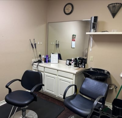 beauty salon with two chairs and a large vanity with a mirror