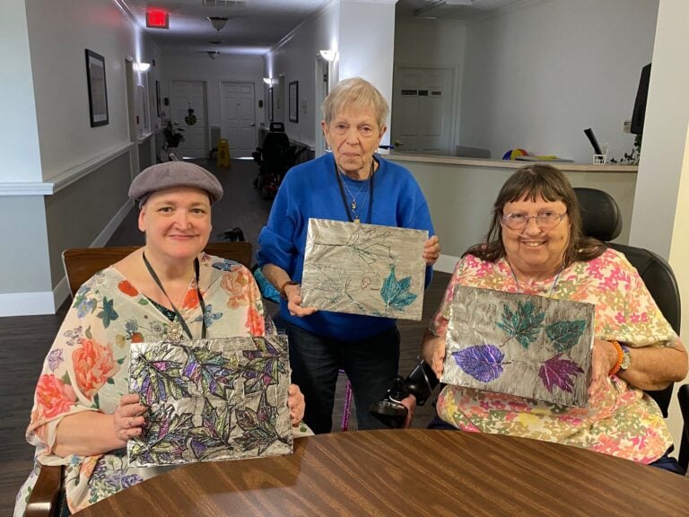 three senior women pose with their completed leaf craft