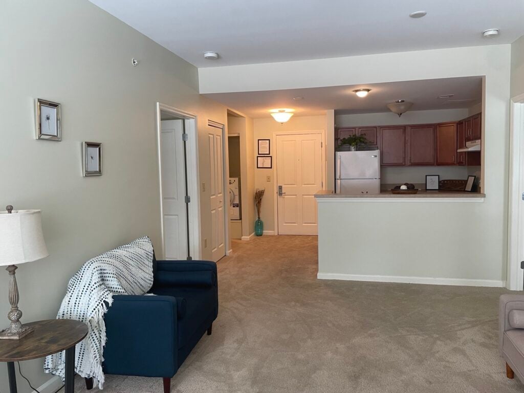 senior living apartment includes a living room with a couch, kitchen near the front door, and laundry