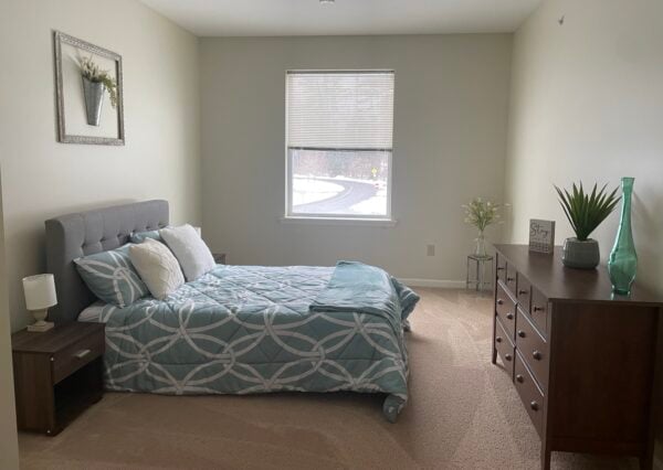senior living apartment bedroom with a bed, night stands, dresser and window