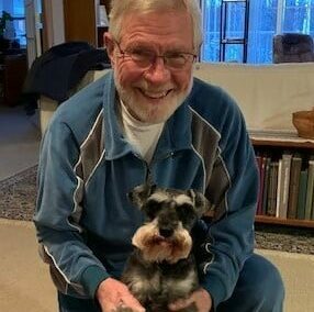 Senior man smiles with his small dog at a senior living community in Fitchburg, Wisconsin.