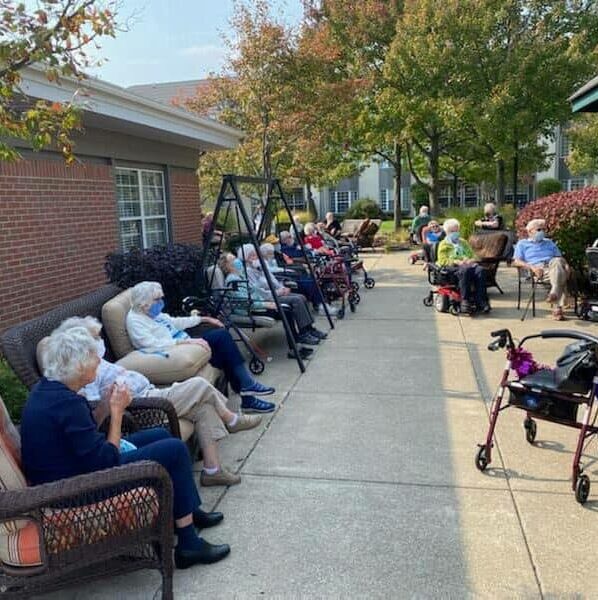 Large gathering of seniors outside on a patio listening to music at senior living facility in Williamsville, New York.