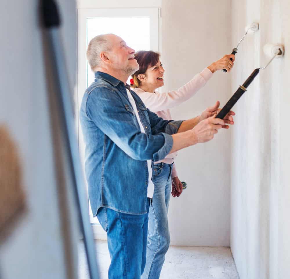 Couple painting a wall in a room.