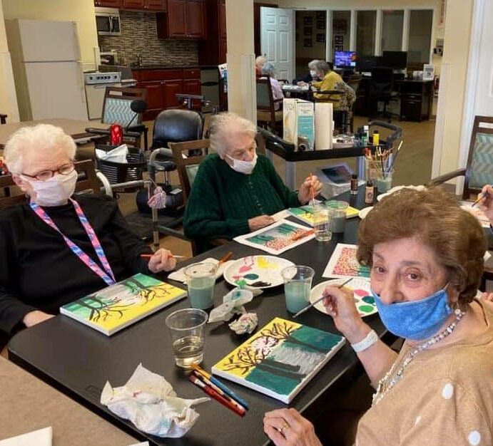 Four senior women painting together at a table at a senior living facility in Williamsville, New York.