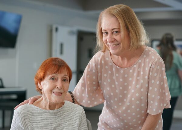 Female employee puts her arm around a senior resident in the activity room