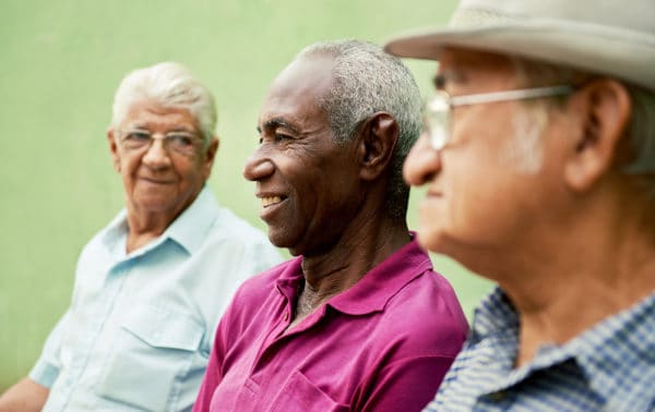 Three senior men sitting next to each other talking.