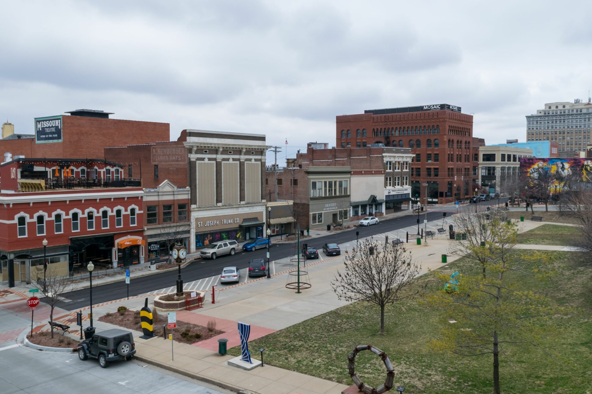 Felix Street Square in downtown St. Joseph, MIssouri. View of cars parked, sculptures, and local business in the background.