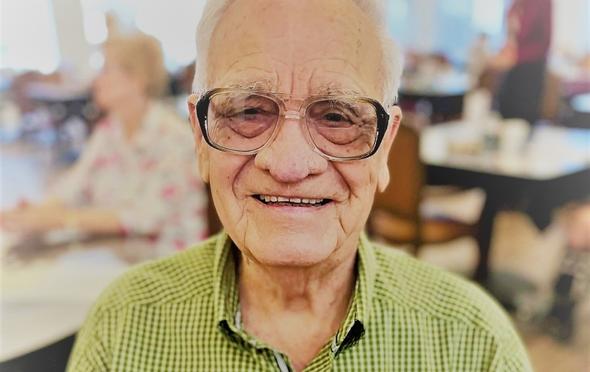 Senior man smiles while sitting in the senior living community dining room