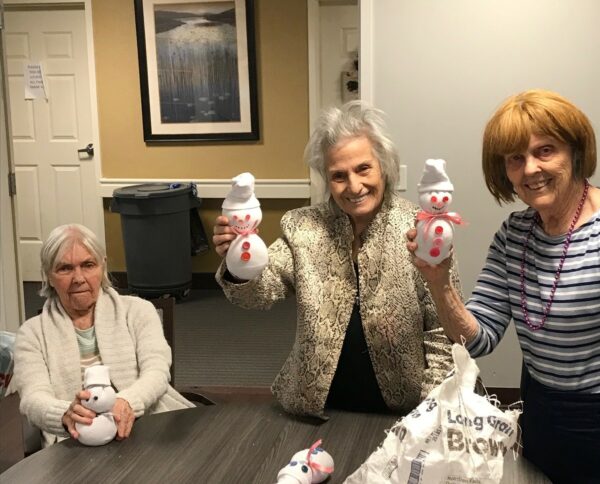 three senior women show off their snowman craft