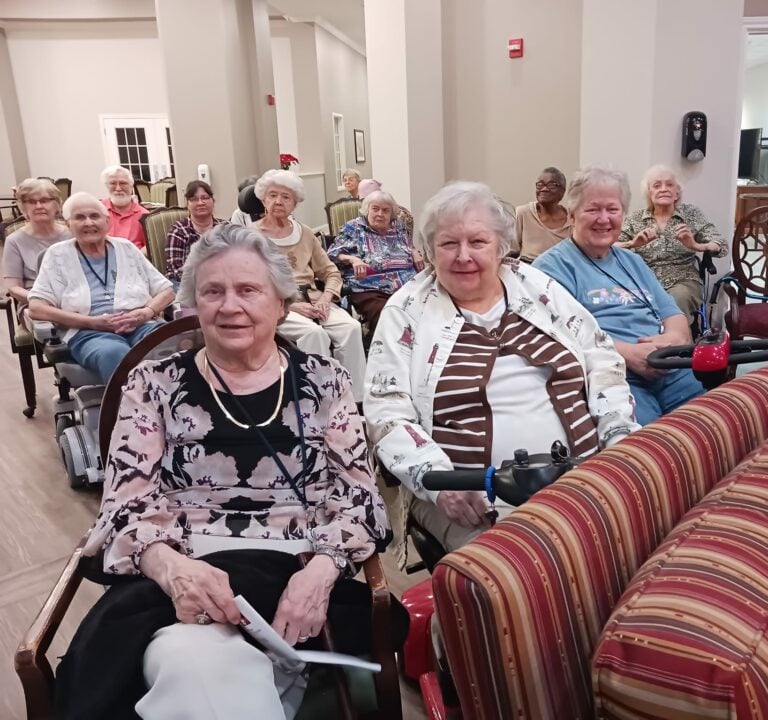 group of seniors sit and attend a show on-site at their senior living community