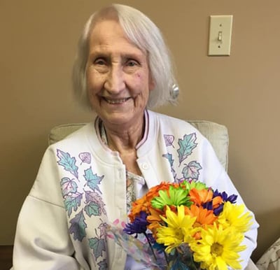 Senior woman smiles with some flowers at a senior living community in West Bend, Wisconsin.