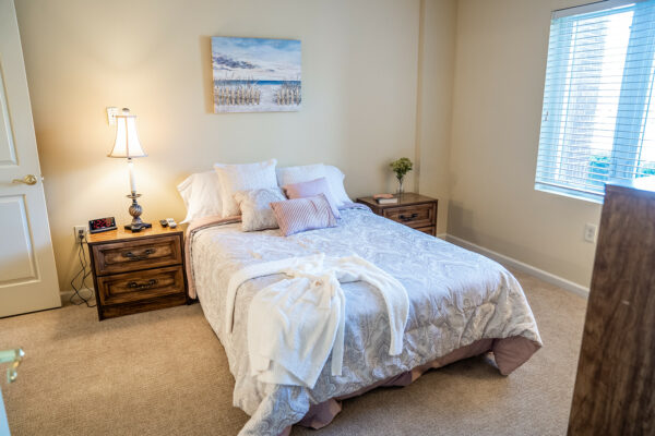 apartment bedroom with a queen bed, two end tables and a large window