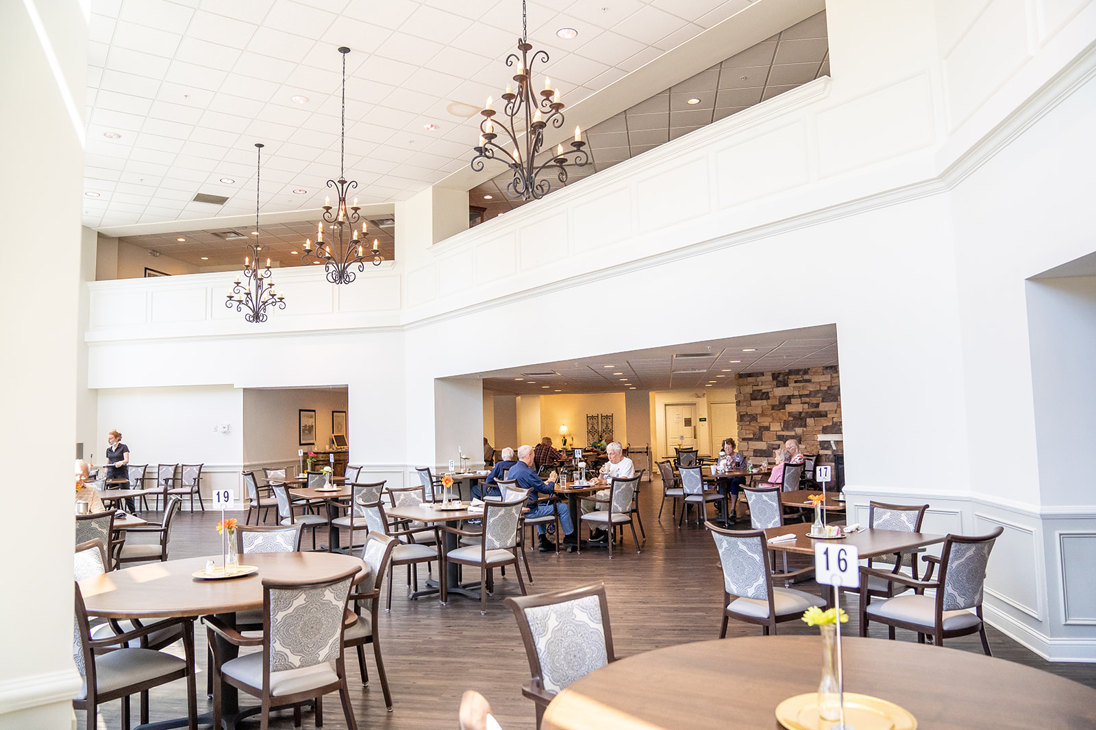 Senior living dining room with multiple tables and chairs to share a meal with friends