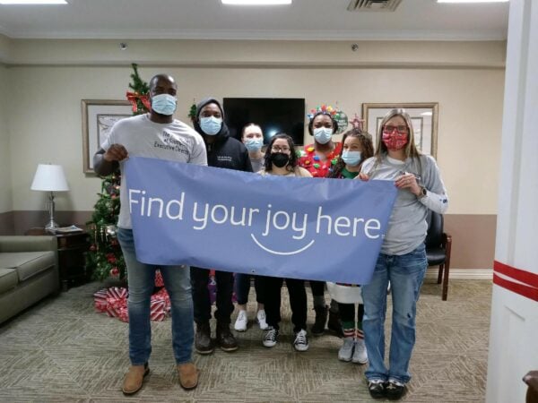 staff members hold a "find your joy here" sign