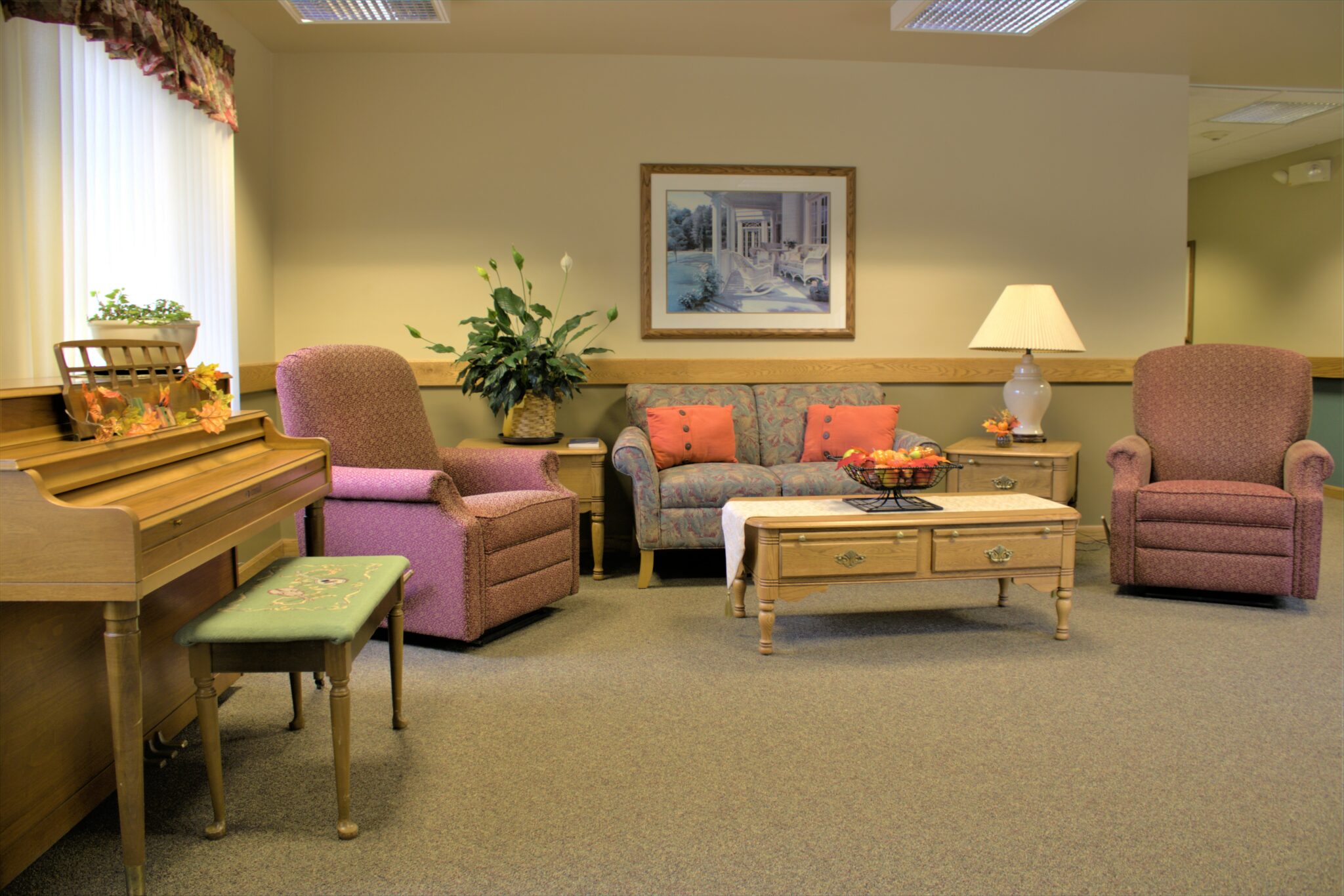 A couch and two chairs sit near a piano in a senior living community in West Bend, Wisconsin