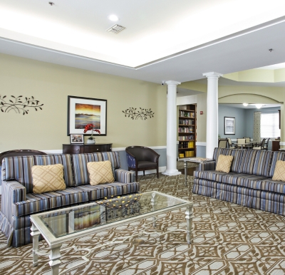 senior living community lounge with two couches, some chairs and a glass table