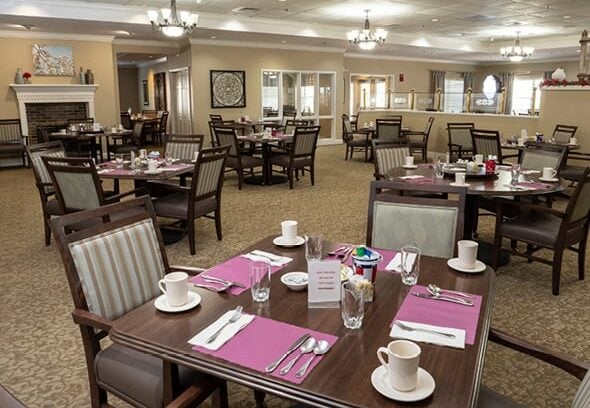 A clean, spacious and bright dining room with many tables and a fireplace in Williamsville, New York