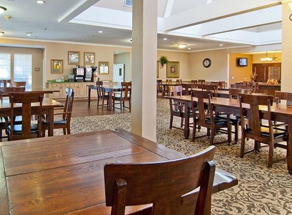 A clean, spacious and well-lit dining area with many table, coffered ceilings and sky lights in Arlington, Texas.