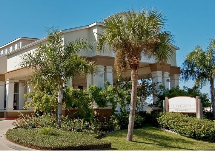 The exterior of The Waterford at Corpus Christi with large palm trees in Corpus Christi, Texas.