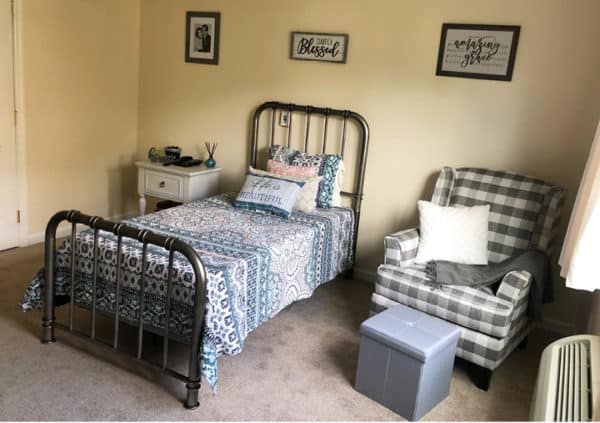 A model apartment bedroom with a twin bed, cozy armchair and a window letting in lots of sunlight in Hamilton, Ohio..