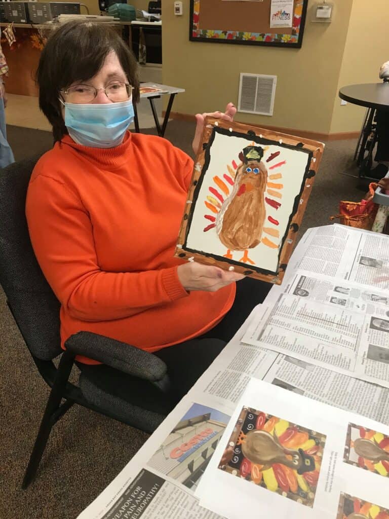 Senior woman poses with her turkey painting.