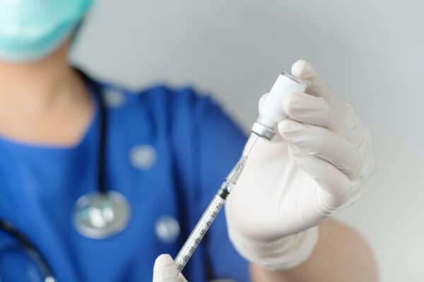 Nurse dispenses a vial of flu vaccine to disperse to patient.