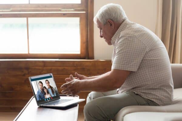 Happy elderly mature man holding video call with grown up children and granddaughter.