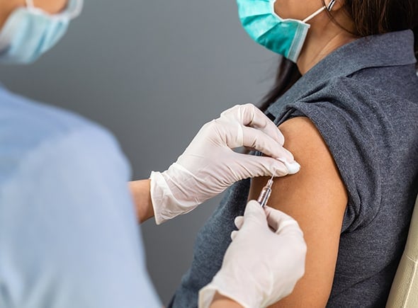 Doctor holding syringe and using cotton before make injection to patient in medical mask.
