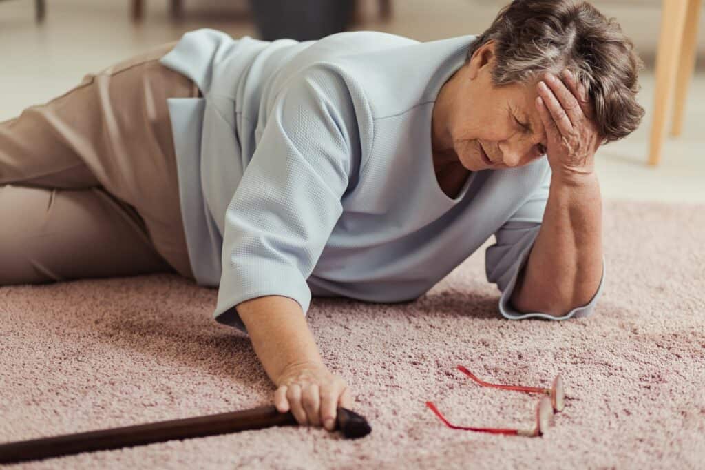 Senior woman lays on the floor after a fall.