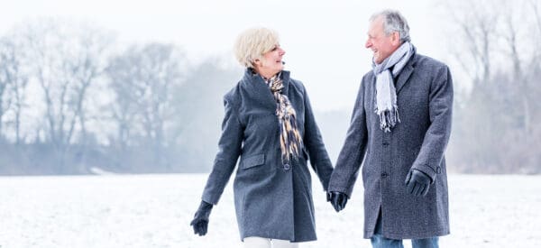 Senior couple having walk in winter wearing scarves and heavy, long coats.