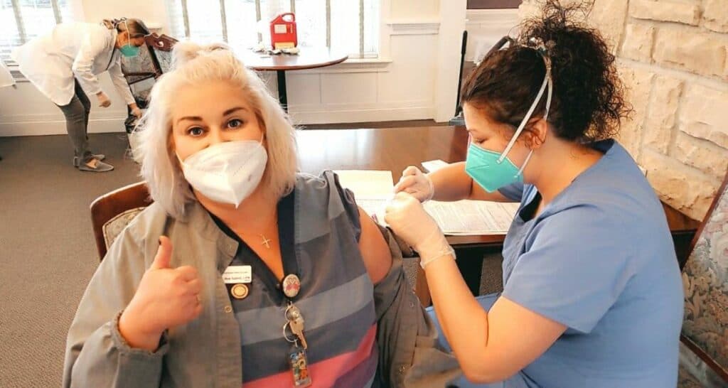 A team member receiving the Covid-19 vaccine and giving a thumbs up.