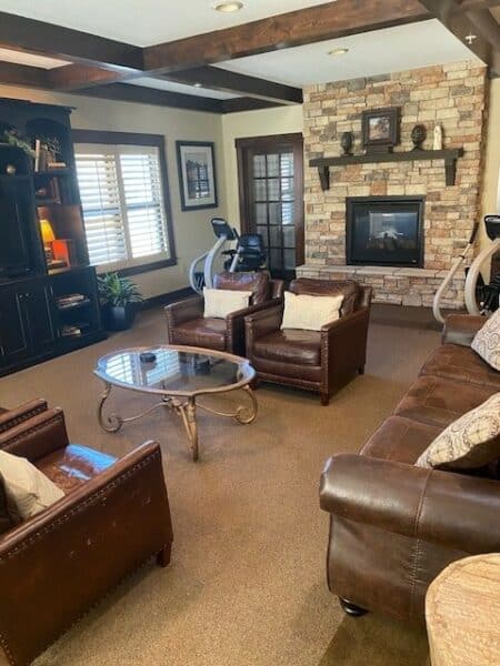 Club room with stationery bike, comfortable couches and fireplace at senior living facility in St. Joseph, Missouri.