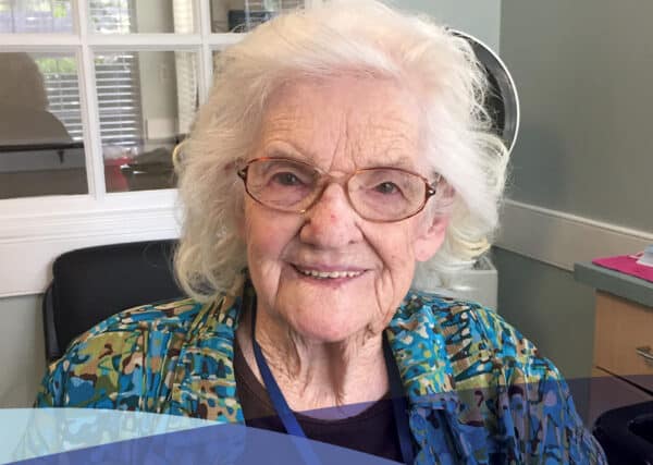 A sonida senior living community resident smiling as she enjoys a sunny day relaxing in the community salon.